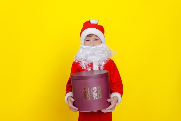 zesjarig blank kind heeft een grote ronde geschenkdoos met de woorden Nieuwjaar 2022 in zijn handen