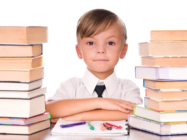 Zesjarige jongen omringd door stapels boeken geïsoleerd tegen een witte achtergrond