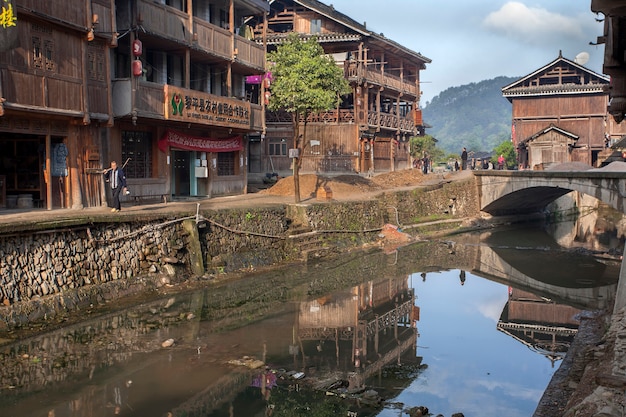 Zhaoxing Dong Village, provincie Guizhou, China Landelijke rivier met geplaveide waterkant omgeven door houten hutten, dorpsminderheid.