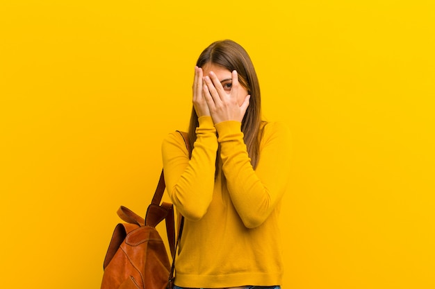 zich bang of beschaamd voelen, gluren of spioneren met ogen die half bedekt zijn met handen