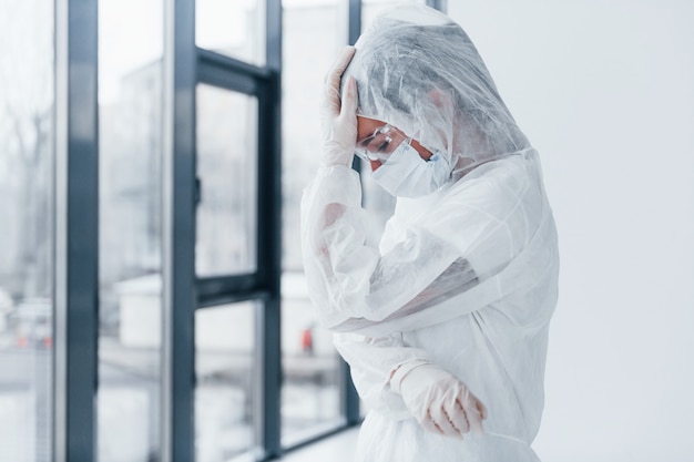 Zich slecht, moe en depressief voelen. Portret van vrouwelijke arts wetenschapper in laboratoriumjas, eyewear verdediging en masker