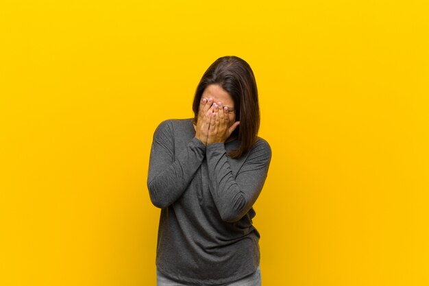 zich verdrietig, gefrustreerd, nerveus en depressief voelen, het gezicht met beide handen bedekkend, huilend