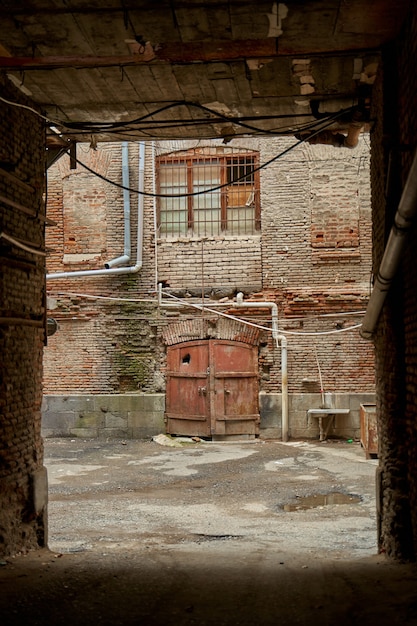 Zicht op de binnenplaats van het oude huis door de toegangsboog. Buitenkant van de oude architectuur.