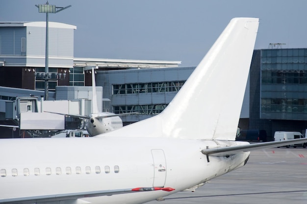 Zicht op de staart van een passagiersvliegtuig en de inschrijvingsterminal van de luchthaven