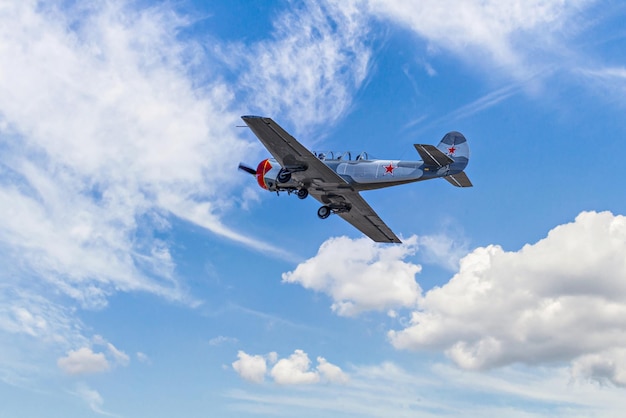 Zicht op een aerobatic aerodyne vliegtuig tijdens de vlucht onder een blauwe lucht met witte wolken