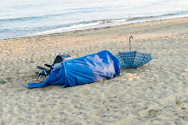 Zicht op een paraplu een opgevouwen tent op een zeestrand