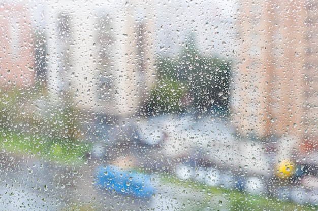 Zicht op regendruppels op de ruit van een stedelijk huis