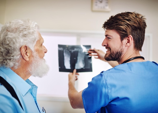 Zie je, er is niets om je zorgen over te maken Shot van een jonge dokter en zijn oudere patiënt die samen naar een röntgenfoto kijken