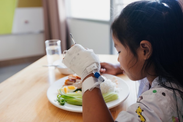 Ziek Aziatisch kindmeisje dat alleen gezond voedsel eet voor de lunch terwijl ze in privépatiëntenkamers in het ziekenhuis verblijft. Gezondheidszorg en lifestyle concept.