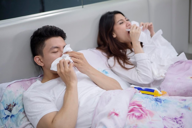 Ziek Aziatisch stel dat in bed niest