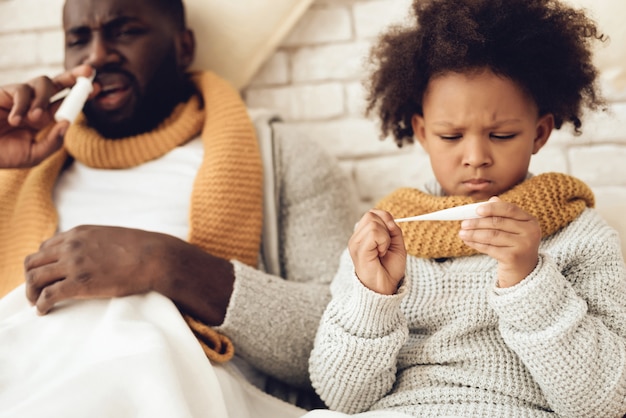 Zieke Afro-Amerikaanse vader en dochter zittend op bed