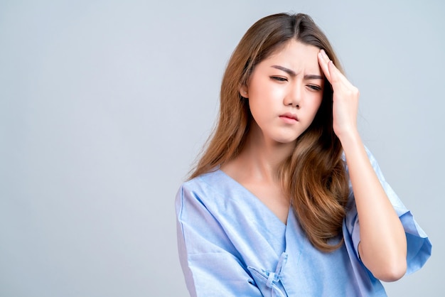 Zieke aziatische vrouwelijke hand raakt lichaamshoofd aan met slecht gevoel hoofdpijn en stress in ziekenhuis uniforme gezondheid en ziekte ideeën concept