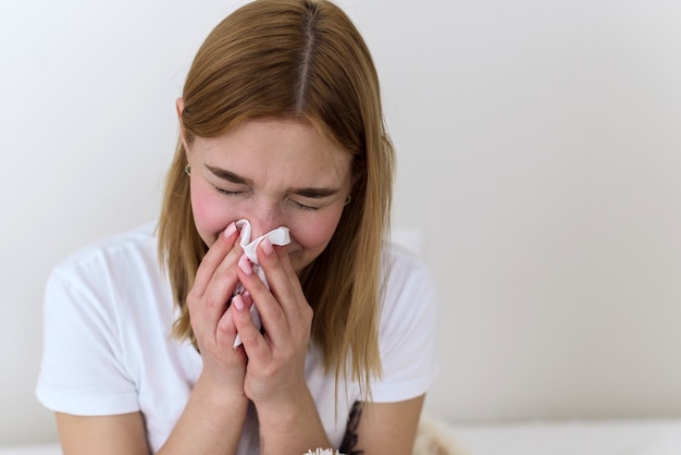Zieke duizendjarige vrouw die zich slecht voelt, zwak vecht tegen griep, loopneus, rust thuis, gezondheidsprobleemconcept. De vrouw snuit haar neus in een zakdoek. depressie, verdriet en huilen.