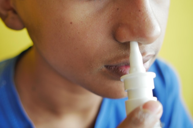 Zieke jongen die nasale medicijnspray gebruikt