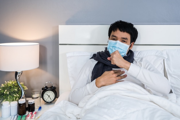 Zieke man in medische masker hoesten en lijden aan virusziekte en koorts in bed, coronavirus pandemisch concept.