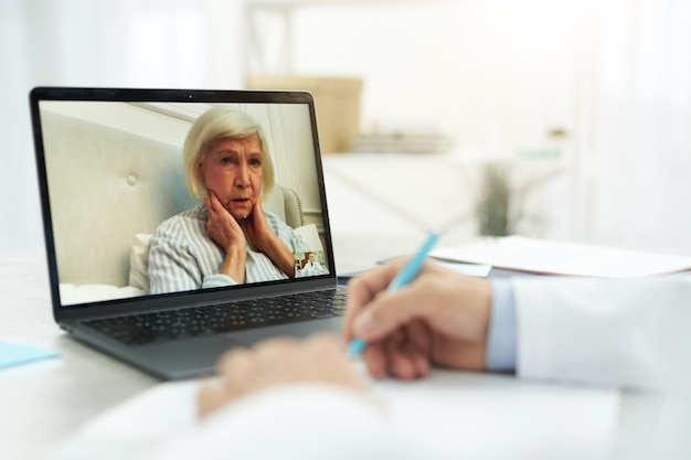 Zieke oude vrouw in gesprek met dokter via videogesprek