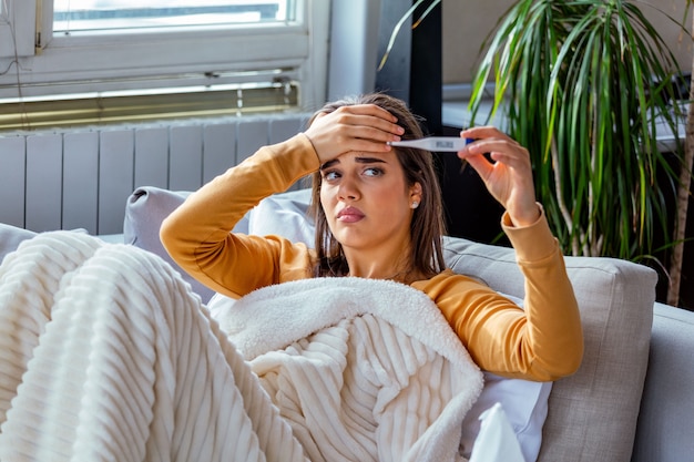 Zieke vrouw die haar temperatuur controleert