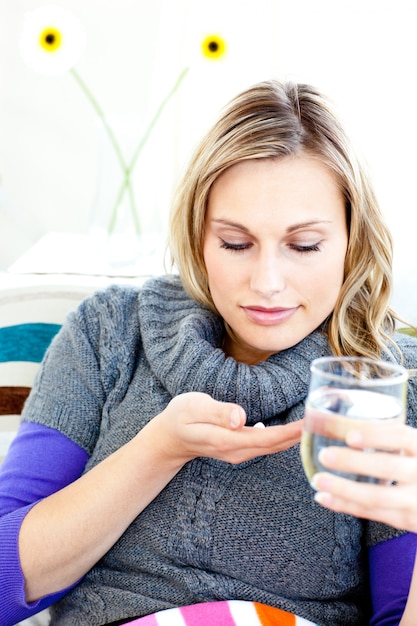 Zieke vrouw die pillen neemt die een glas water houden