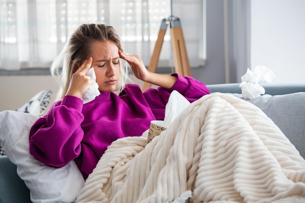 Zieke vrouw met hoofdpijn die onder de deken zit Zieke vrou met seizoensgebonden infecties griepallergie die in bed ligt Zieke vrouw bedekt met een deken die in het bed ligt met hoge koorts en een griep die rusten