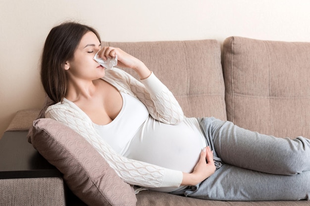 Zieke zwangere vrouw blaast haar neus in weefsel thuis Gezond millennial gezondheidszorgconcept