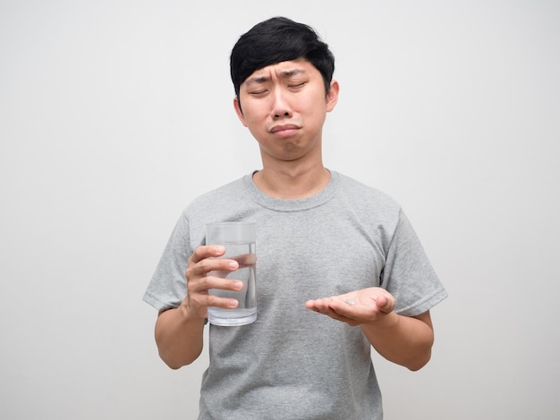 Ziekte man voelt zich verveeld om medicijnen te nemen Aziatische man houdt waterglas vast met medicijnen