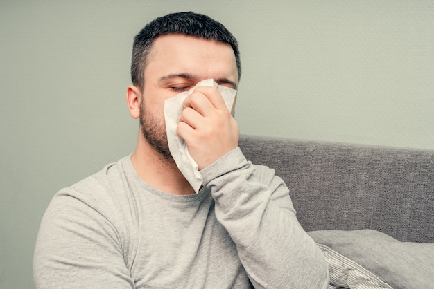 Ziekte. Thuis juichen. Een jonge man is ziek, wordt thuis behandeld. Blaast haar neus in een servet, loopneus. Infectie, epidemie, bacillus-drager.