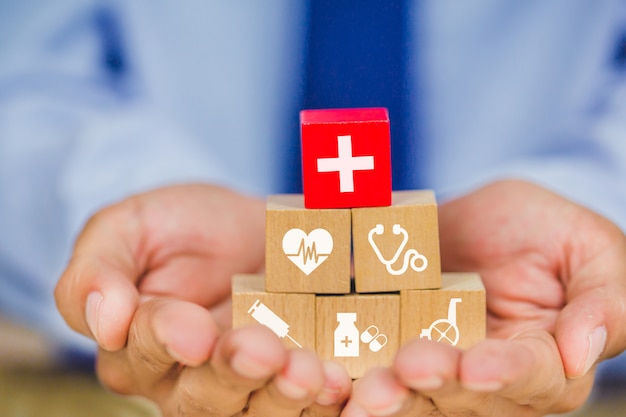 Ziektekostenverzekering concept, hand schikken hout blok stapelen met medische pictogram gezondheidszorg