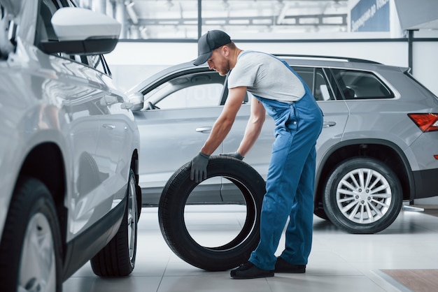 Ziet er pefect uit. Monteur met een band bij de reparatiegarage. Vervanging van winter- en zomerbanden