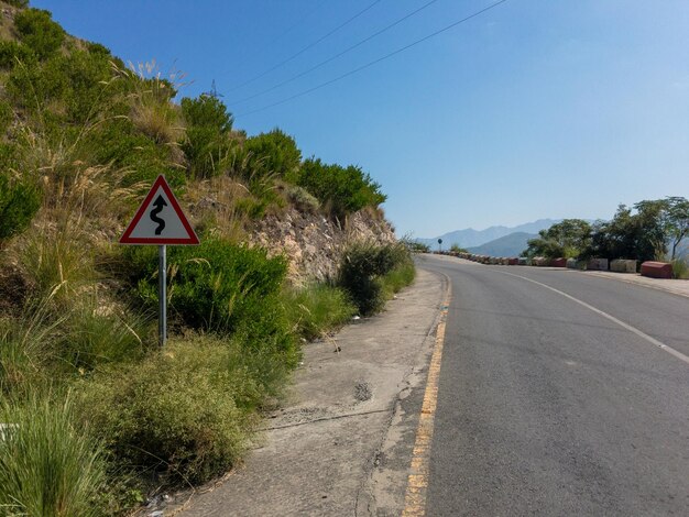 Zig zag road warning sign board on a road side