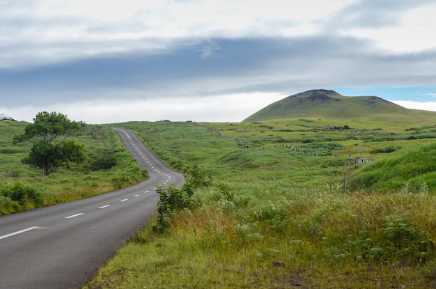 Zigzagging road in the countryside of Easter Island with some volcanic formations on the horizon