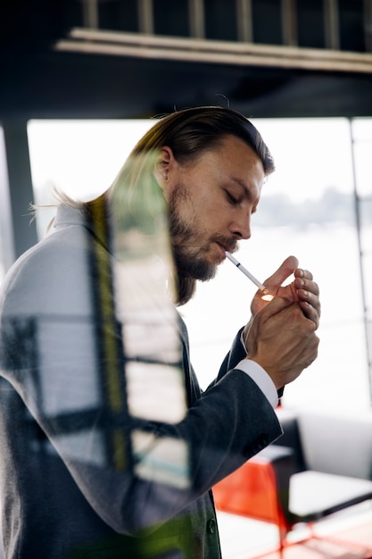 Zijaanzicht bij jonge zakenman die van zijn sigaar geniet