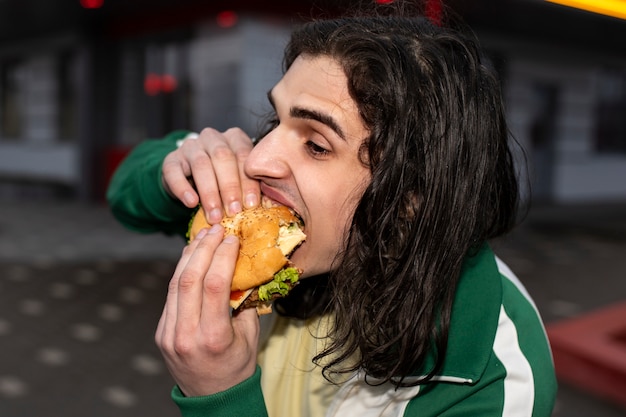 Zijaanzicht man hamburger eten