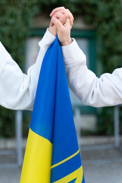 Zijaanzicht mensen hand in hand met Oekraïense vlag