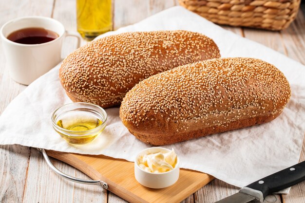 Zijaanzicht op loafs van tarwe en roggebrood met boter op de houten achtergrond