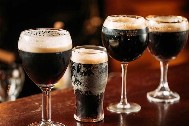 Zijaanzicht op verschillende glazen met donker getapt bier op het bureau aan de bar