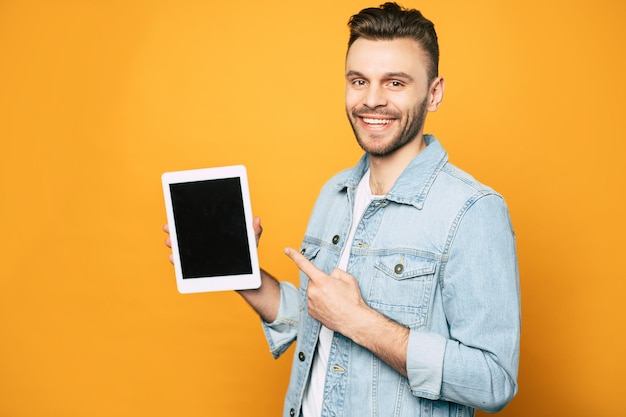 Zijaanzicht portret van casual zakenman met moderne tablet in handen over gele achtergrond