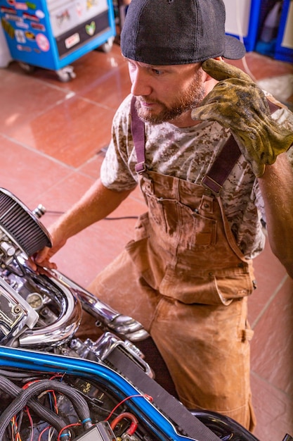 Zijaanzicht portret van man aan het werk in garage motorfiets repareren en aanpassen