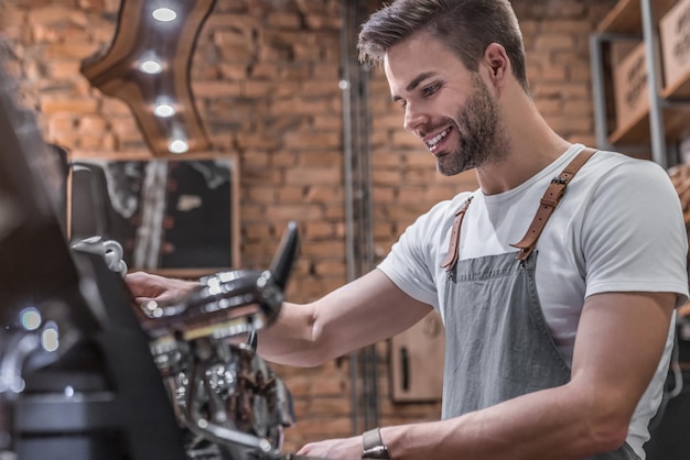 Zijaanzicht shot van een mannelijke barista die een kopje koffie maakt