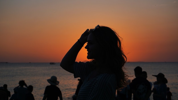 Zijaanzicht van achterlicht van een vrouw silhouet warme zonsondergang voor zon - toeristenstrand bij zonsondergang