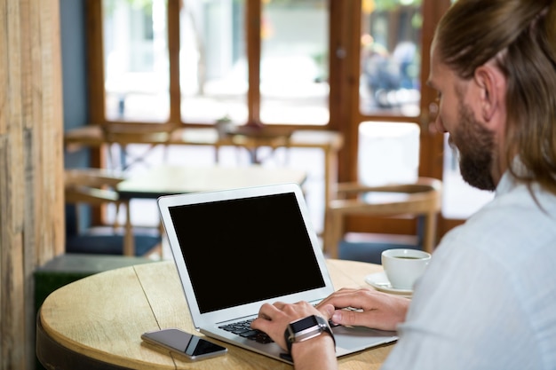 Zijaanzicht van de jonge man met laptop in de coffeeshop