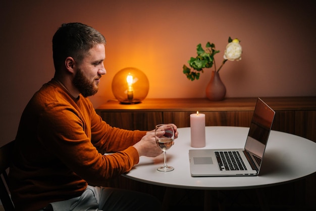 Zijaanzicht van een gelukkige jonge man die een videogesprek voert met behulp van een laptopcomputer die een ring presenteert en een huwelijksaanzoek op afstand doet