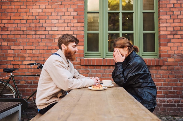 Zijaanzicht van een jong stel dat graag koffie drinkt terwijl ze samen rusten in het straatcafé