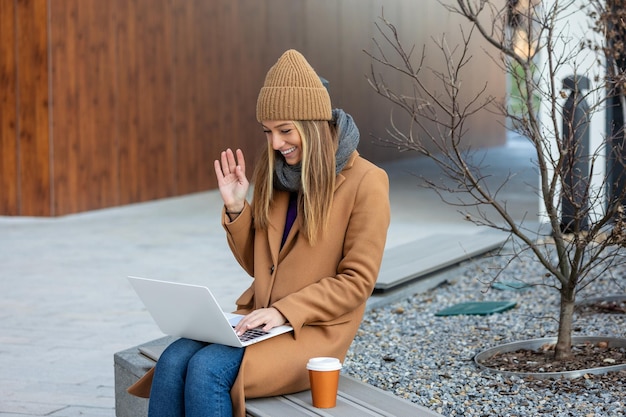 Zijaanzicht van een jonge vrouw die online chat op een laptopcomputer die op een bank zit jonge vrouwelijke freelancer die op sociale media chat