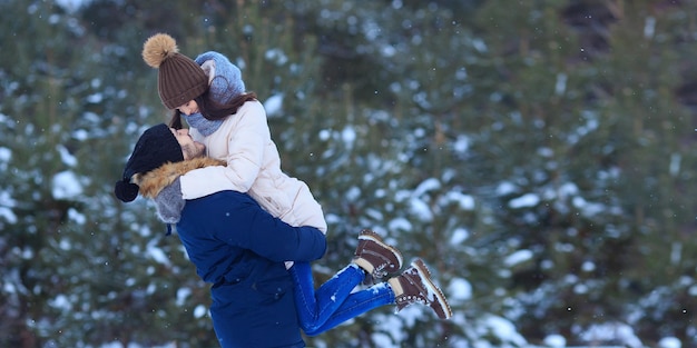 Zijaanzicht van een man met een gelukkige vriendin die in een prachtig besneeuwd bos staat en elkaar liefdevol aankijkt