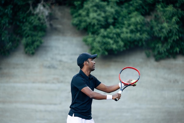 Zijaanzicht van een tennisspeler die op een buitenbaan speelt