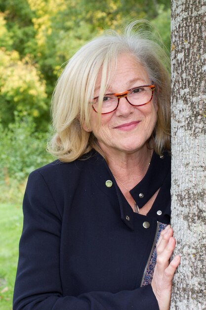 Foto zijaanzicht van een volwassen vrouw leunend tegen boomstam