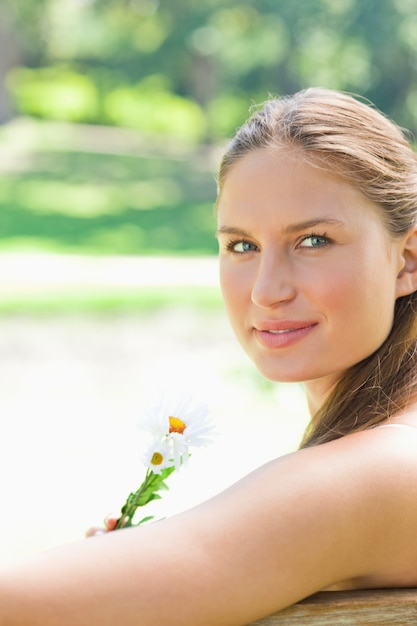 Foto zijaanzicht van een vrouw die een bloem in het park houdt