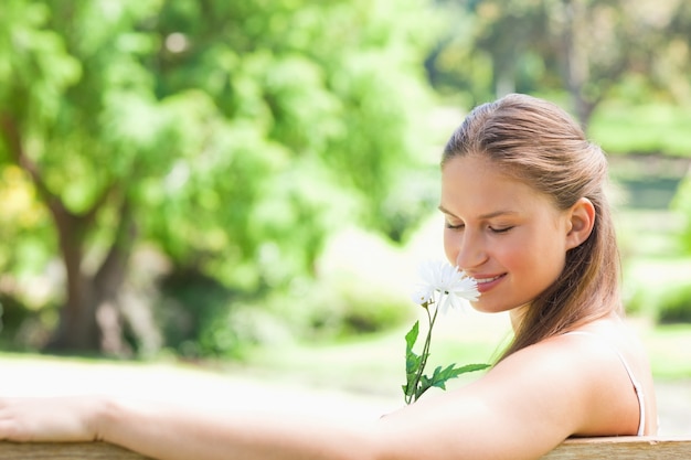 Foto zijaanzicht van een vrouw die een bloem ruikt