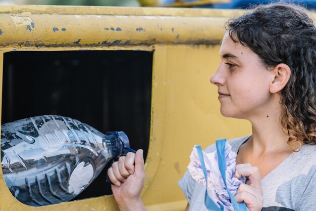 Zijaanzicht van een vrouw die lacht en plastic flessen recycleert. recyclingconcept