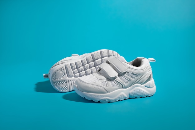 Zijaanzicht van een witte unisex sneaker met klittenband die voor de zool van een andere staat...